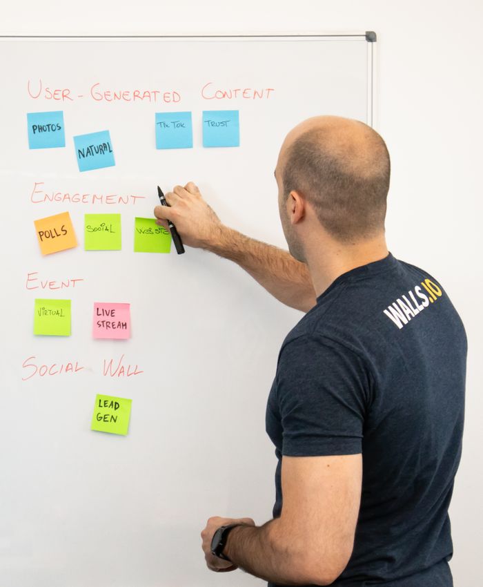 Un homme analyse des stratégies de contenu marketing à l’aide de post-it sur un tableau blanc.